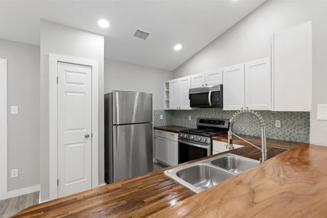 a kitchen with granite countertop a stove a microwave a sink and cabinets