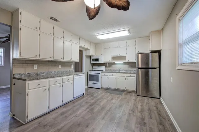 a kitchen with granite countertop white cabinets and stainless steel appliances