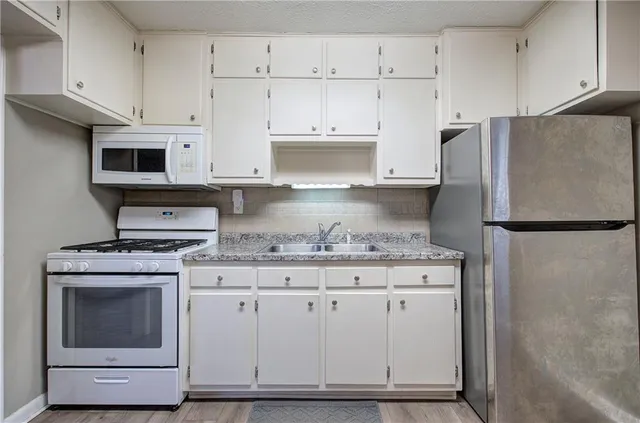 a kitchen with granite countertop a stove sink and refrigerator