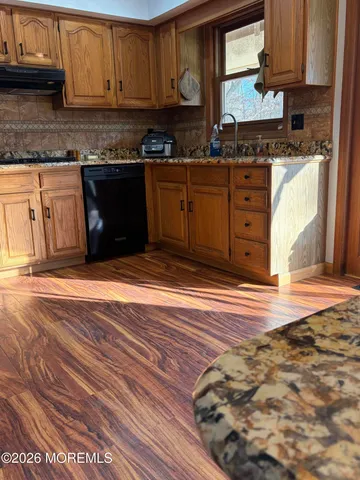 a kitchen with granite countertop wooden cabinets and a wooden floor