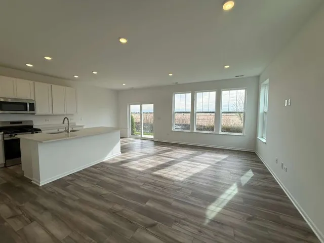 a large white kitchen with kitchen island a sink wooden floor and a window