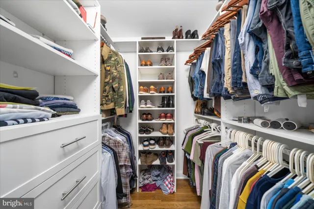 a view of walk in closet with clothes and shoes