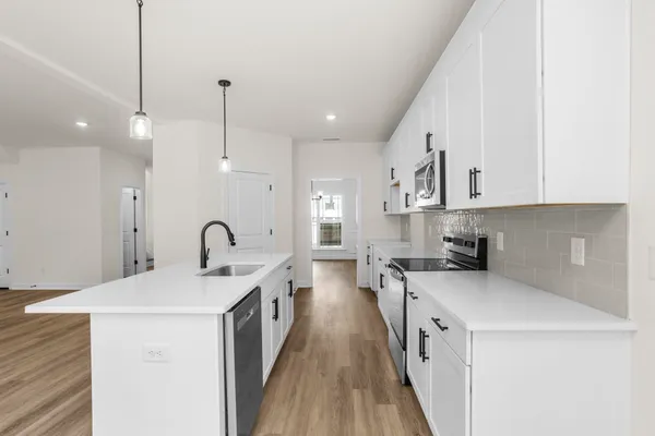 a kitchen with stainless steel appliances a sink a stove top oven a counter space and cabinets
