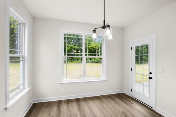 an empty room with wooden floor a ceiling fan and windows
