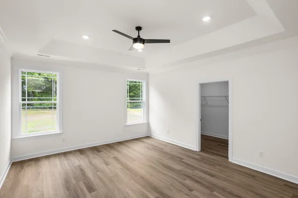 an empty room with wooden floor ceiling fan and windows