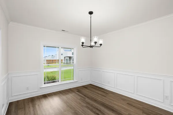 a view of a room with wooden floor chandelier and windows