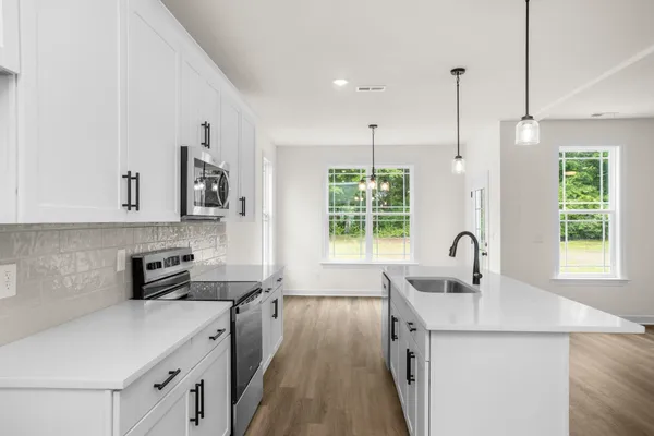 a kitchen with a sink chandelier and wooden floor