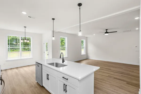a kitchen with stainless steel appliances white cabinets a sink a stove a refrigerator and a center island