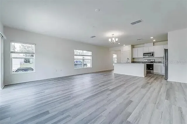 a view of an empty room with kitchen appliances and a window