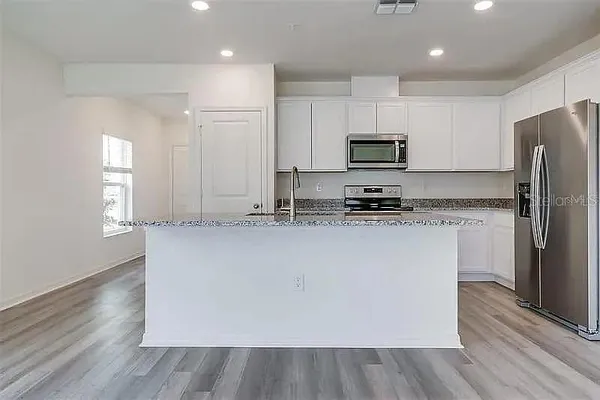 a kitchen with kitchen island white cabinets and stainless steel appliances
