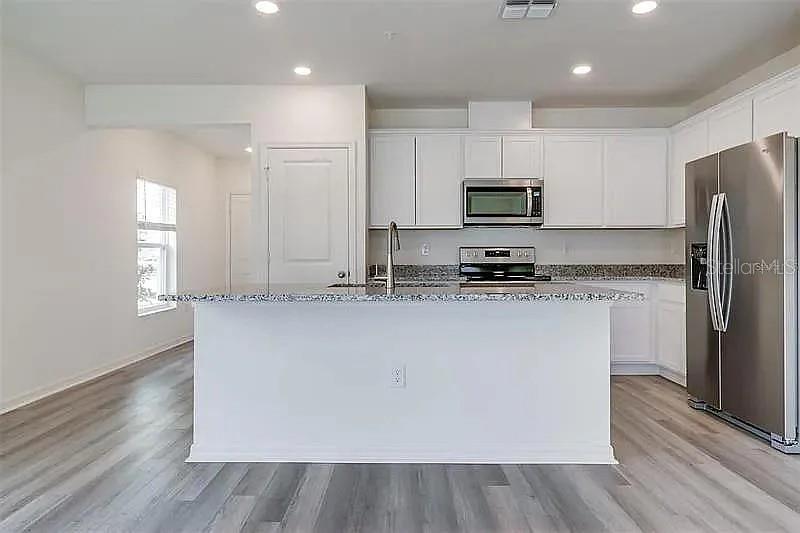 2302 Carrabelle Way Sanford, FL 32771 - Photo 8 of 24 a kitchen with kitchen island white cabinets and stainless steel appliances