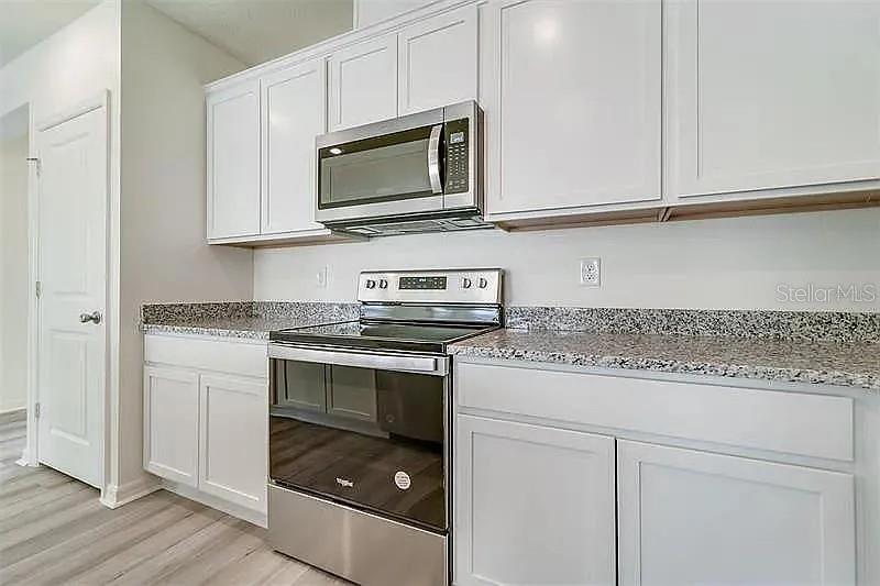 2302 Carrabelle Way Sanford, FL 32771 - Photo 9 of 24 a kitchen with stainless steel appliances granite countertop white cabinets sink and stove