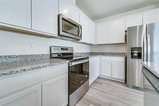 a kitchen with granite countertop cabinets stainless steel appliances and wooden floor