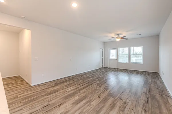 a view of an empty room with wooden floor and a window