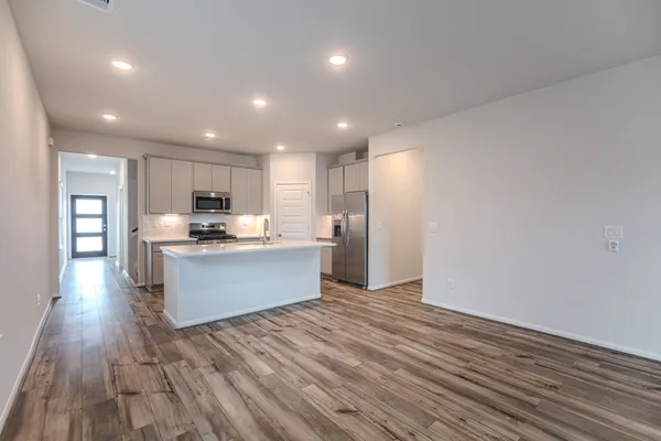 a large kitchen with stainless steel appliances a large counter top and wooden floors