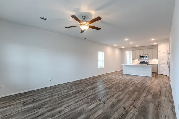 a view of kitchen and empty room with wooden floor