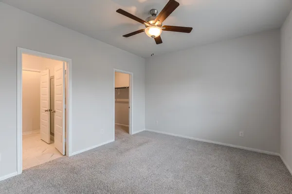 an empty room with closet and a ceiling fan
