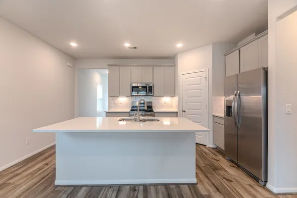 a kitchen with kitchen island a counter top space a sink cabinets stainless steel appliances and cabinets