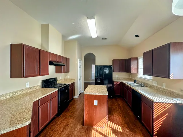a kitchen with stainless steel appliances granite countertop wooden cabinets a stove top oven a sink and dishwasher