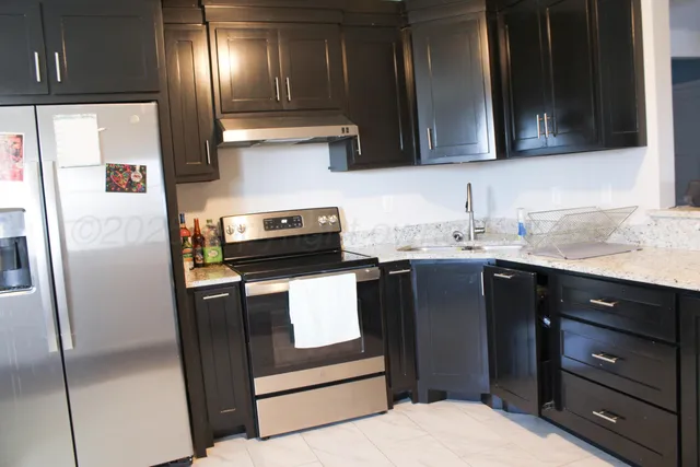 a kitchen with stainless steel appliances granite countertop a refrigerator a stove a sink and a microwave