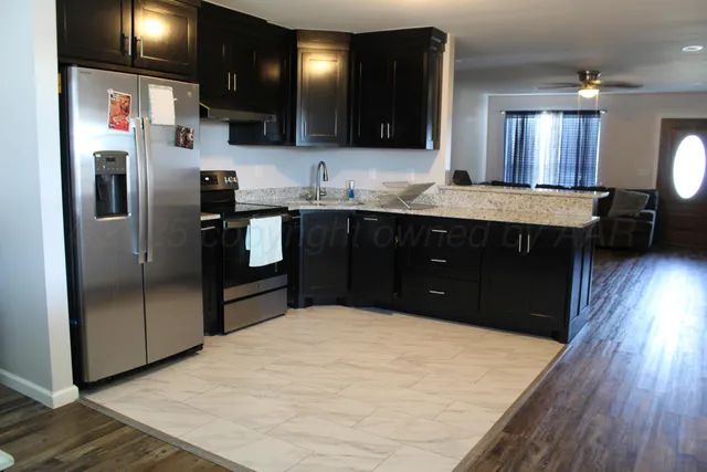 a kitchen with stainless steel appliances granite countertop a refrigerator a sink a stove and oven