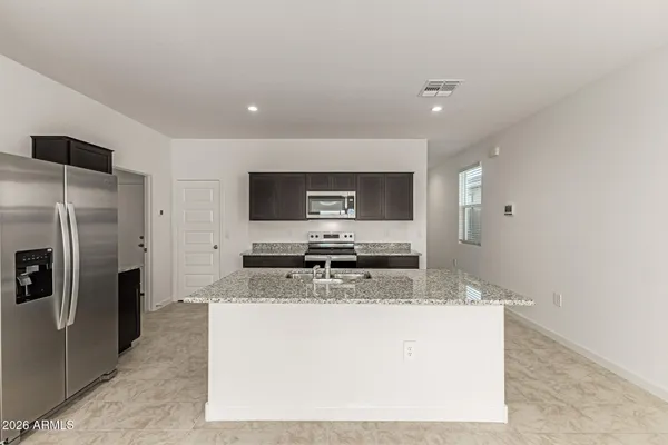 a kitchen with stainless steel appliances granite countertop a sink a stove a refrigerator a washer and dryer