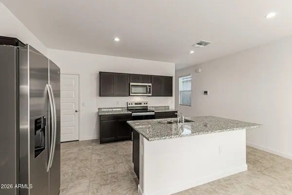 a kitchen with stainless steel appliances granite countertop a refrigerator a stove and a sink