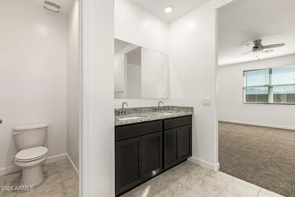 a bathroom with a granite countertop sink toilet and mirror