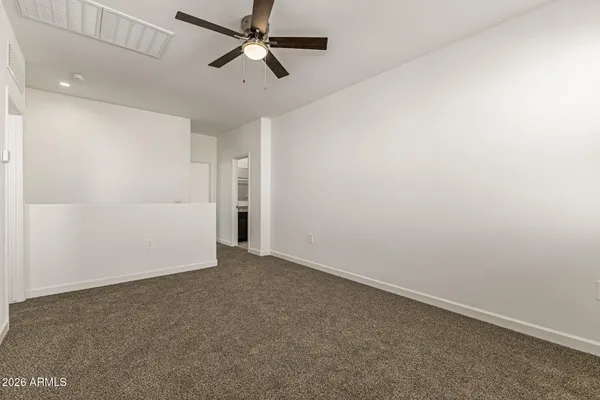 an empty room with a ceiling fan and carpet