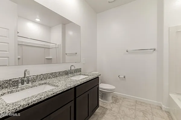 a bathroom with a granite countertop sink a toilet and a mirror