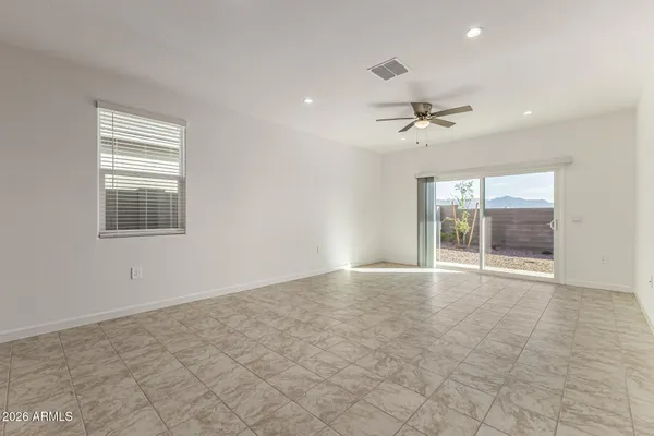 an empty room with chandelier fan and windows