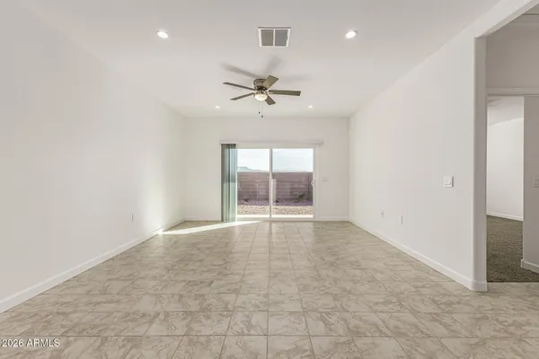 an empty room with chandelier fan and windows