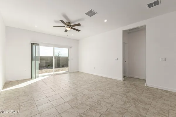 an empty room with chandelier fan and windows