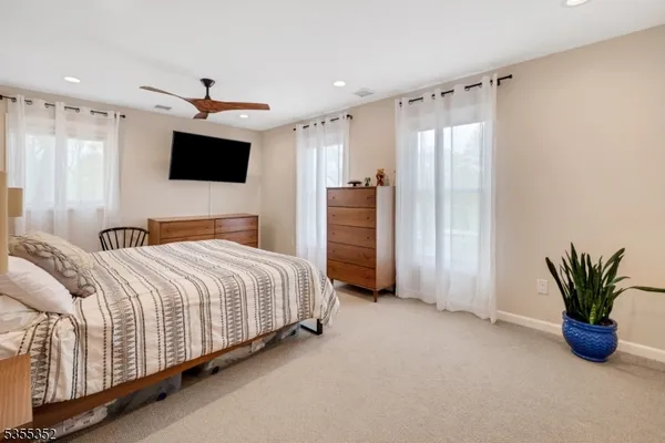 a bedroom with a large bed a flat tv screen and a couch