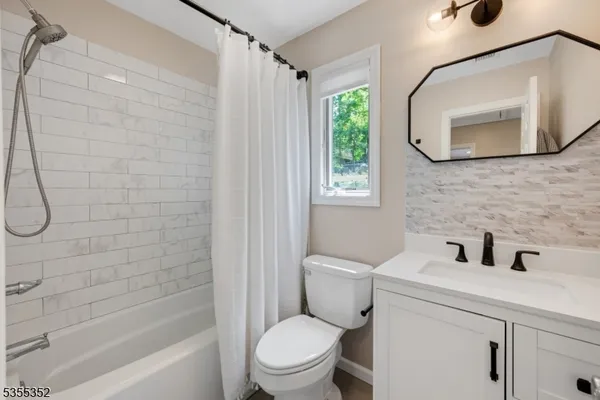 a bathroom with a toilet sink vanity tub and mirror