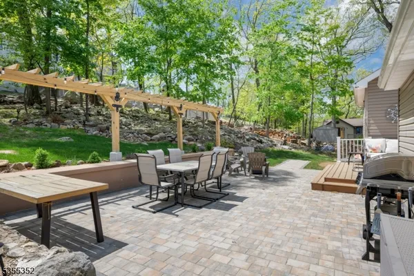 a view of a patio with table and chairs and potted plants and large trees