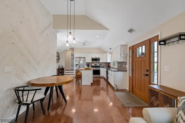 a kitchen with stainless steel appliances kitchen island granite countertop a dining table chairs and a refrigerator