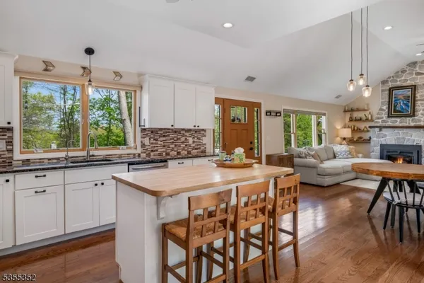a kitchen with granite countertop lots of white furniture wooden floor and a window