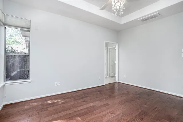 an empty room with a chandelier fan and windows