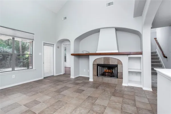 a view of an empty room with a fireplace and window