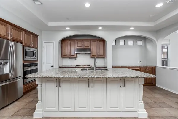 a kitchen with stainless steel appliances granite countertop a stove a sink and a refrigerator