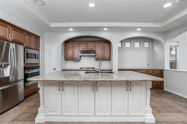 a kitchen with stainless steel appliances granite countertop a stove a sink and a refrigerator