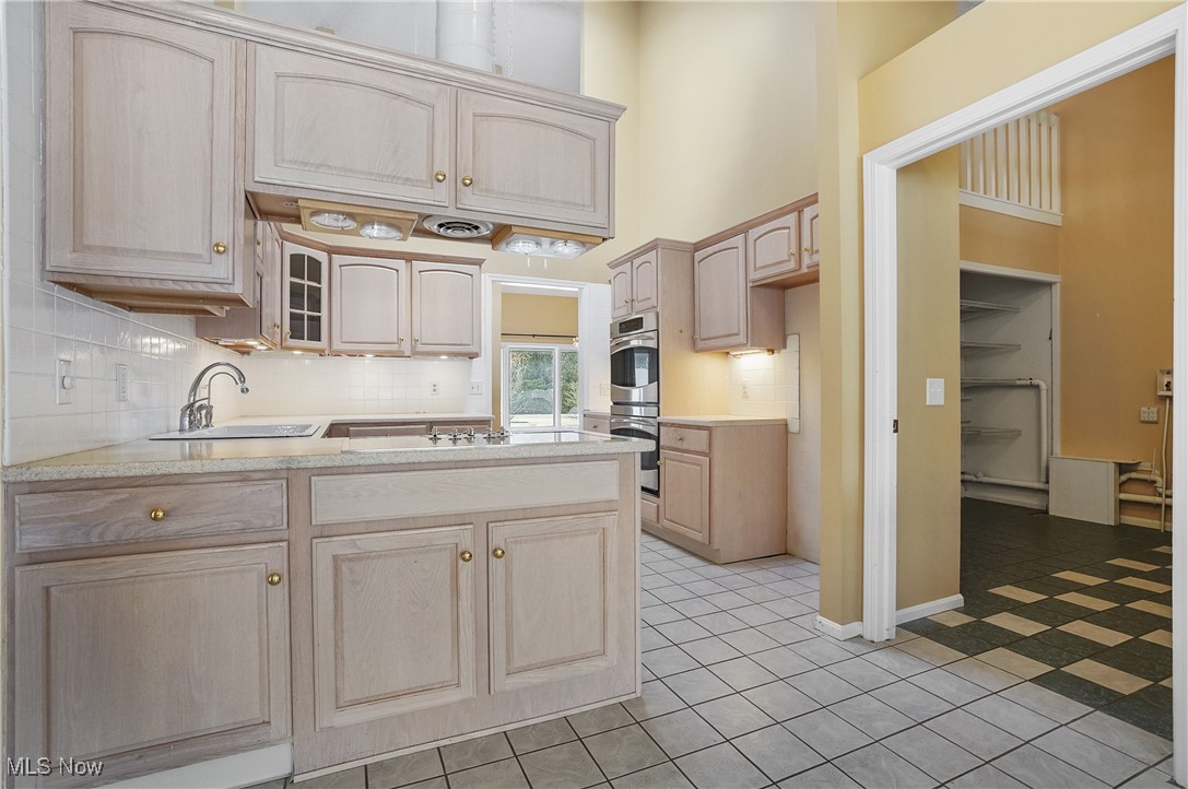 1094 San Raphael Drive Akron, OH 44333 - Photo 22 of 50 Kitchen with light brown cabinetry, a peninsula, glass insert cabinets, tasteful backsplash, and a high ceiling