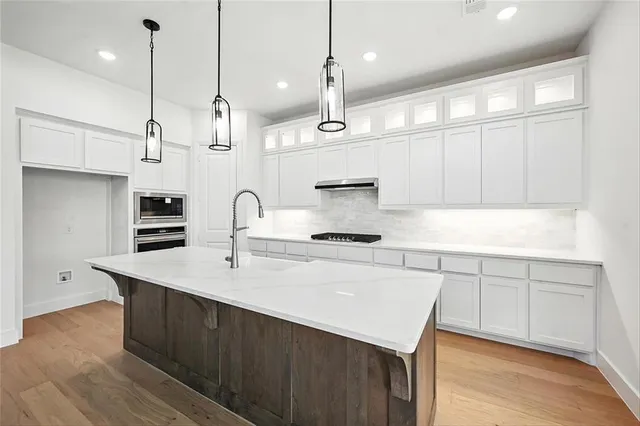 a kitchen with stainless steel appliances granite countertop a sink a stove and a wooden floors