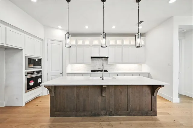 a kitchen with kitchen island a sink appliances and a counter top space