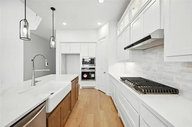 a kitchen with stainless steel appliances a sink a stove a refrigerator and cabinets