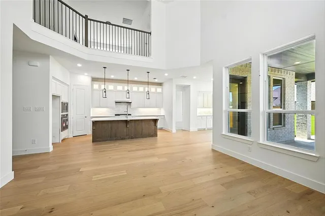 a view of a kitchen with kitchen island a sink wooden floor and a large window