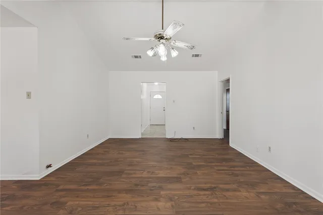 a view of an empty room with chandelier fan