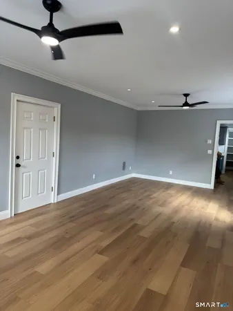 a view of a livingroom with a ceiling fan wooden floor and window