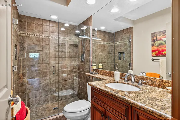 a bathroom with a granite countertop sink a toilet a shower and bathtub